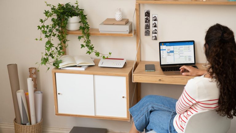 Eine Person sitzt vor einem Laptop, auf einem Regal neben ihr steht eine FritzBox.