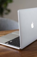 Ein MacBook steht geöffnet auf einem Schreibtisch.