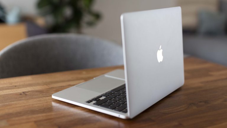 Ein MacBook steht geöffnet auf einem Schreibtisch.
