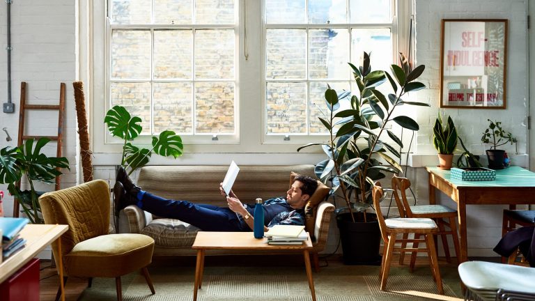 NAS einrichten Eine Person liegt auf einem Sofa und hält ein Laptop in den Händen.
