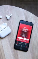 Auf einem kleinen Tisch liegen ein iPhone und AirPods Pro.