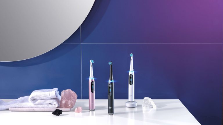 Elektrische Zahnbürsten Drei Modelle der iO-Serie von Oral-B stehen auf einem Badezimmerschrank.