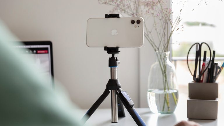 iPhone als Webcam Ein iPhone ist in die Halterung eines Dreibein-Stativs eingespannt und auf eine Person gerichtet.