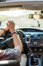 Zwei Personen sitzen in einem Auto und scheinen sich zu Musik zu bewegen. An der Mittelkonsole ist ein Smartphone angesteckt.