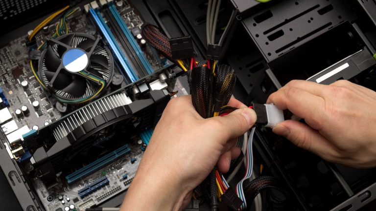 Computer reparieren Eine Person überprüft die Steckverbindung von Komponenten in einem Rechner.