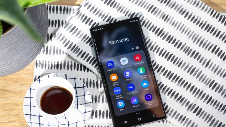 Samsung Galaxy S22 Ultra Ein Samsung Galaxy S22 Ultra liegt mit dem Display nach oben auf einer Tischdecke. Daneben steht eine Tasse Kaffee.