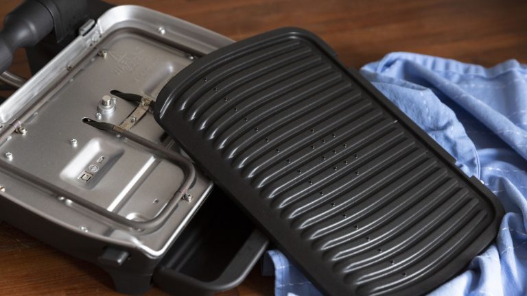 Tefal Optigrill Elite Aus einem aufgeklappten Tefal Optigrill wurde die untere Heizplatte herausgenommen und danebengelegt. So lässt sich sie mühelos reinigen.