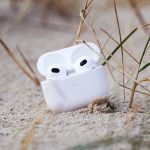 AirPods der dritten Generation in ihrem Case liegen auf einer Sandbank.