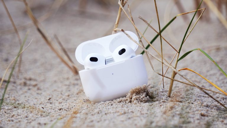 AirPods der dritten Generation in ihrem Case liegen auf einer Sandbank.