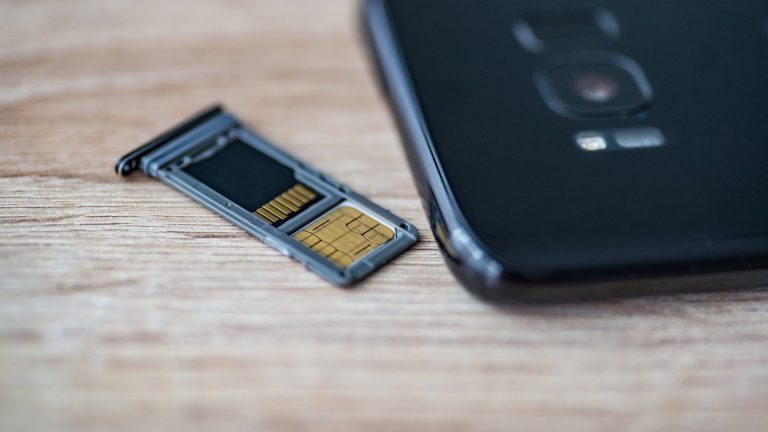 Android Speicher voll Neben einem Smartphone liegt der Einschub für die SIM-Karte. Darin befinden sich eine SIM-Karte und eine microSD-Karte.