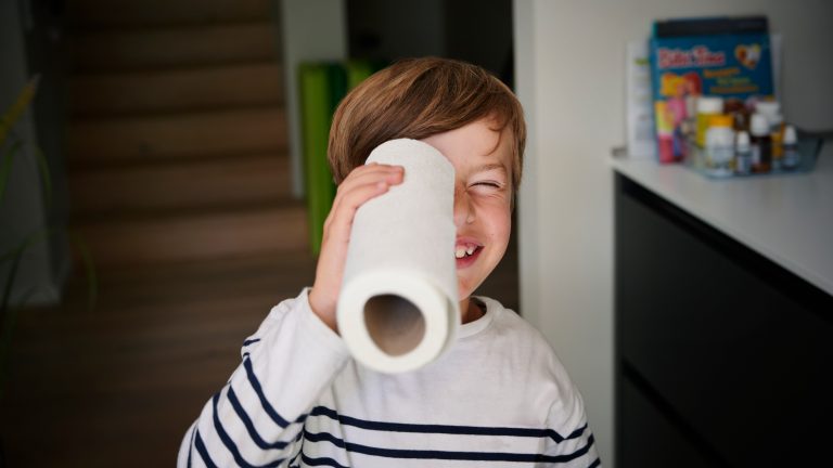 Fritteuse reinigen Eine Person hält sich eine Küchenpapierrolle wie ein Fernrohr vors Auge.