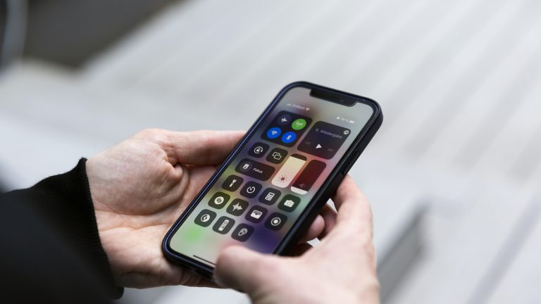 iPhone Gesten Eine Person hält ein iPhone 12 in den Händen, auf dem gerade das Kontrollzentrum zu sehen ist.
