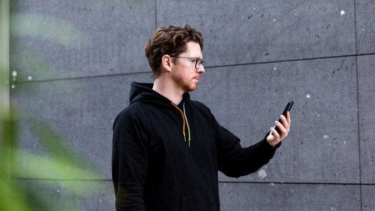 iPhone Gesten Eine Person hält ein iPhone 12 in der Hand, um es per Face ID zu entsperren.