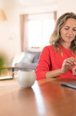 Eine Person sitzt an einem Tisch und bedient ein Smartphone.