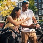 Zwei Personen auf Fahrrädern machen eine kurze Pause und schauen gemeinsam auf ein Smartphone.