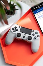 Ein PS4-Controller liegt neben einem iPhone auf einer Schale.