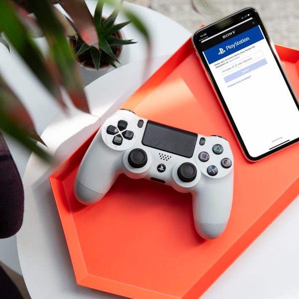 Ein PS4-Controller liegt neben einem iPhone auf einer Schale.