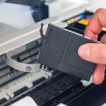 Eine Hand holt eine Druckerpatrone aus einem Drucker.