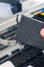 Eine Hand holt eine Druckerpatrone aus einem Drucker.
