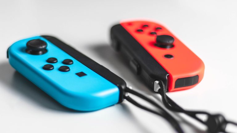 Nintendo Switch Auf einer weißen Oberfläche liegen Joy-Cons in den Farben Blau und Rot.