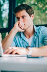 Eine Person sitzt vor einem Laptop und blickt angestrengt auf den Bildschirm.