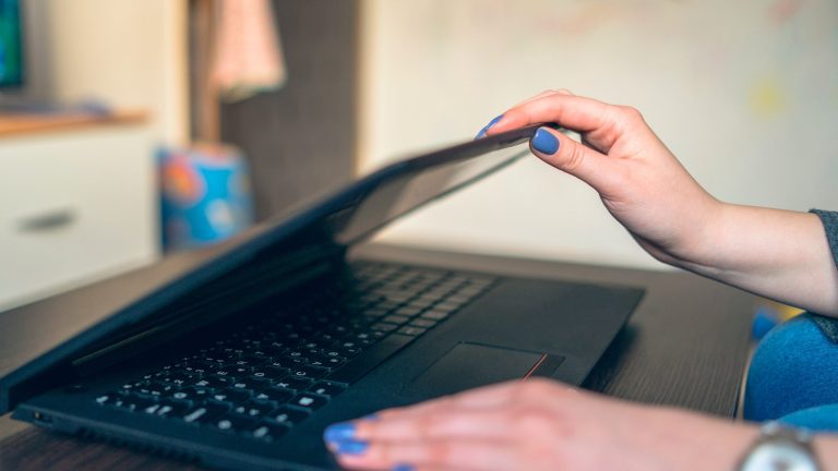 Windows Speicherplatz freigeben Eine Person an einem Schreibtisch schließt ihren Laptop.