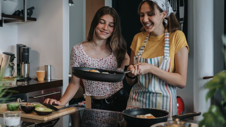 Kochfeld Zwei Frauen stehen vor dem Herd und kochen Spiegelei in einer Pfanne.