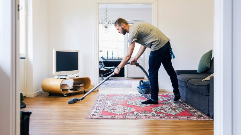 Eine Person saugt den versiegelten Parkettboden in einem Wohnzimmer.