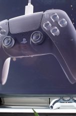 Der DualSense-Controller vor einen Fernseher.