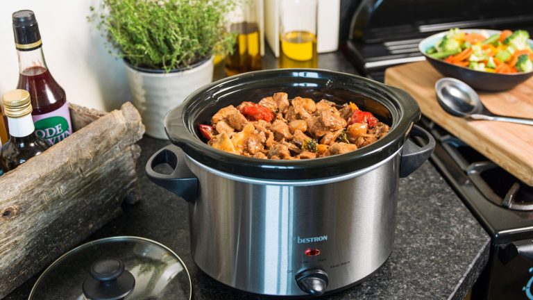 bestron Schongarer ASC350 Ein geöffneter Slow-Cooker-Kochtopf steht in einer Küche auf einer Arbeitsplatte. Im Topf befinden sich einige Zutaten.