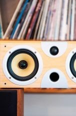 Eine Subwoofer-Box ohne Abdeckung steht auf zwei Regallautsprechern.