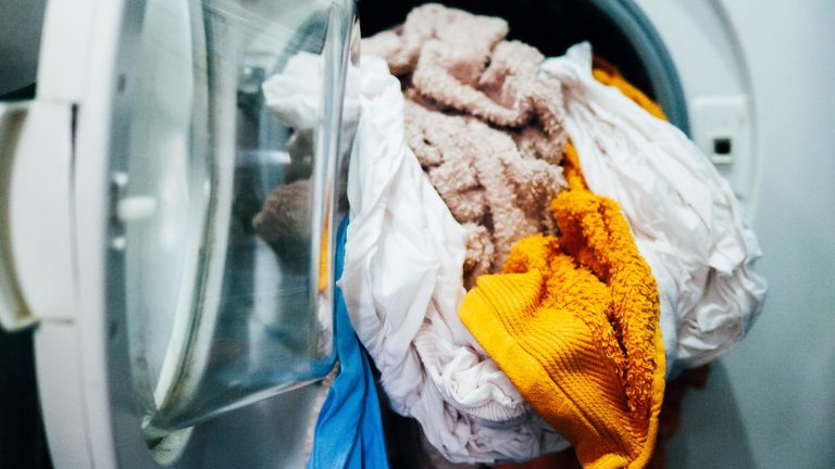 Wäschetrockner stinkt In einer geöffneten Waschmaschine liegen nasse Bettlaken und Handtücher.