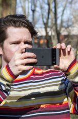 Eine Person hält ein Google Pixel in der Hand und macht damit draußen ein Foto.