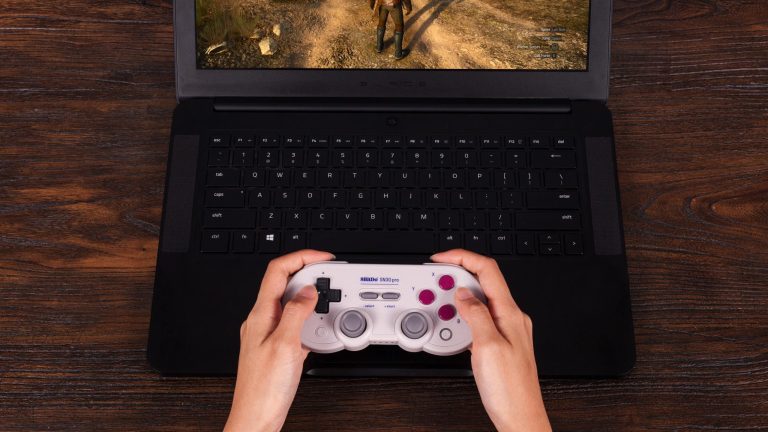 SN30 Pro ine Person hält einen SN30 Pro von 8BitDo in der Hand und spielt damit auf einem Laptop.