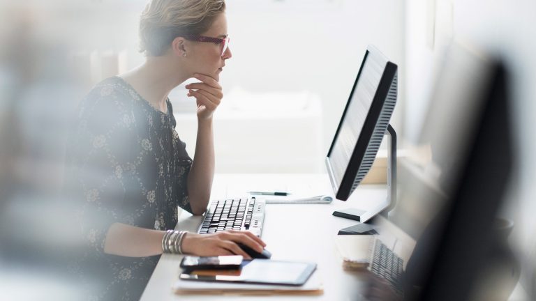 Eine Person sitzt an einem Schreibtisch vor einem Monitor und einer Tastatur und hält eine Maus in der Hand. Tastatur gesperrt