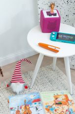 Eine Toniebox, eine Nintendo Switch Lite und ein Tiptoi-Stift auf einem kleinen Tisch.