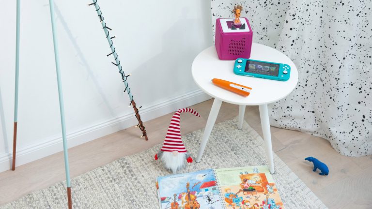 Eine Toniebox, eine Nintendo Switch Lite und ein Tiptoi-Stift auf einem kleinen Tisch.