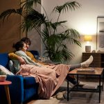 Zwei Personen sitzen auf einem Sofa unter einer Decke und schauen gemeinsam etwas an.