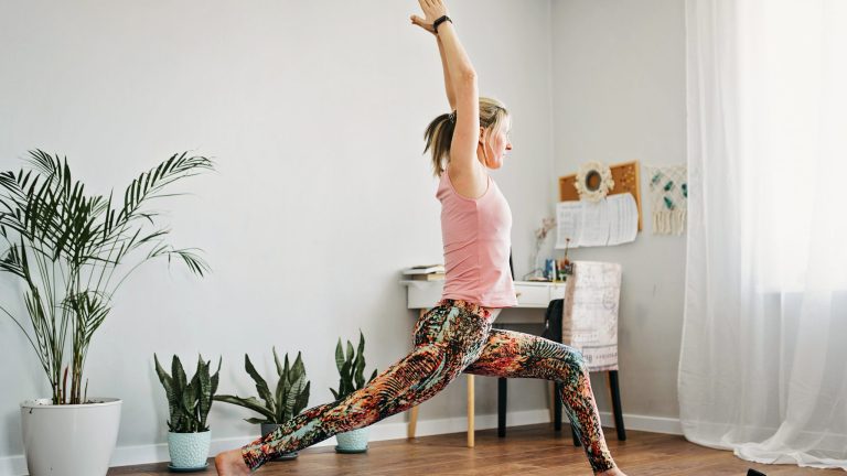 kostenlose Fitness Apps Eine Person macht eine Yoga-Übung, die vor ihr auf dem Smartphone angezeigt werden.