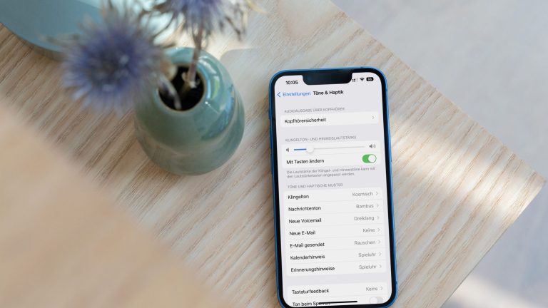 iPhone Wecker Lautstärke Ein Smartphone liegt neben einer Vase auf einem Holztisch.