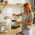 Eine Person gießt etwas Kaffee aus einer Filtermaschine in eine Tasse.