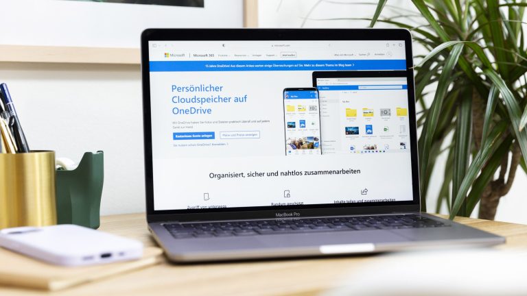 Ein MacBook Pro mit geöffneter OneDrive-Produktseite steht auf einem Tisch.