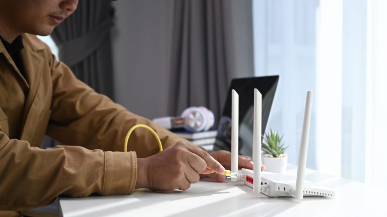 Eine Person steckt ein LAN-Kabel in einen Router.