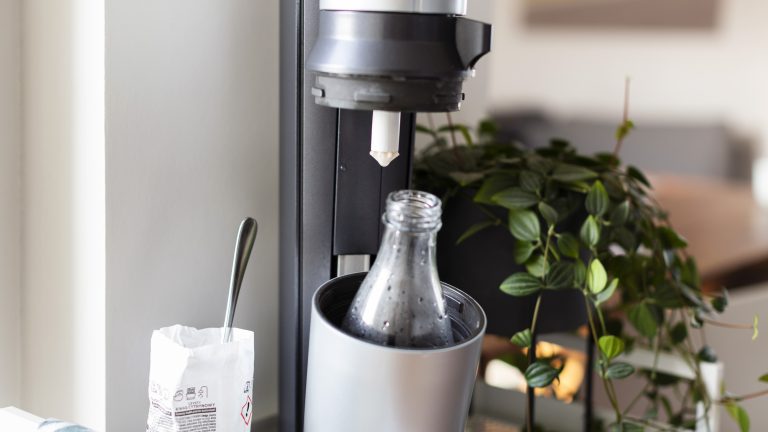 Eine Glasflasche befindet sich in der Öffnung des SodaStreams.
