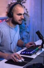 Eine Person sitzt vor einem Gaming-Rechner und spielt etwas.