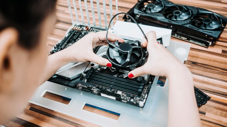 Young woman repairing and assembling pc computer Eine Person montiert einen CPU-Lüfter auf ein Mainboard.