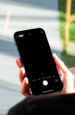 Eine Person blickt auf ein iPhone, welches sie in der rechten Hand hält.