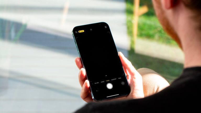Eine Person blickt auf ein iPhone, welches sie in der rechten Hand hält.