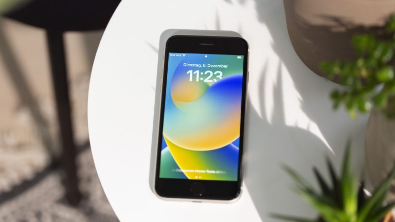 Ein iPhone SE mit angezeigtem Sperrbildschirm liegt auf einem Tisch.