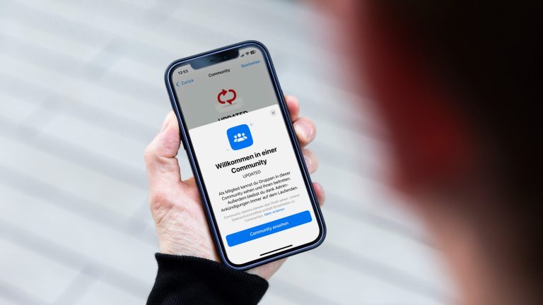 Eine Person hält ein iPhone in der Hand, auf dem die neue Community-Funktion von WhatsApp zu sehen ist.